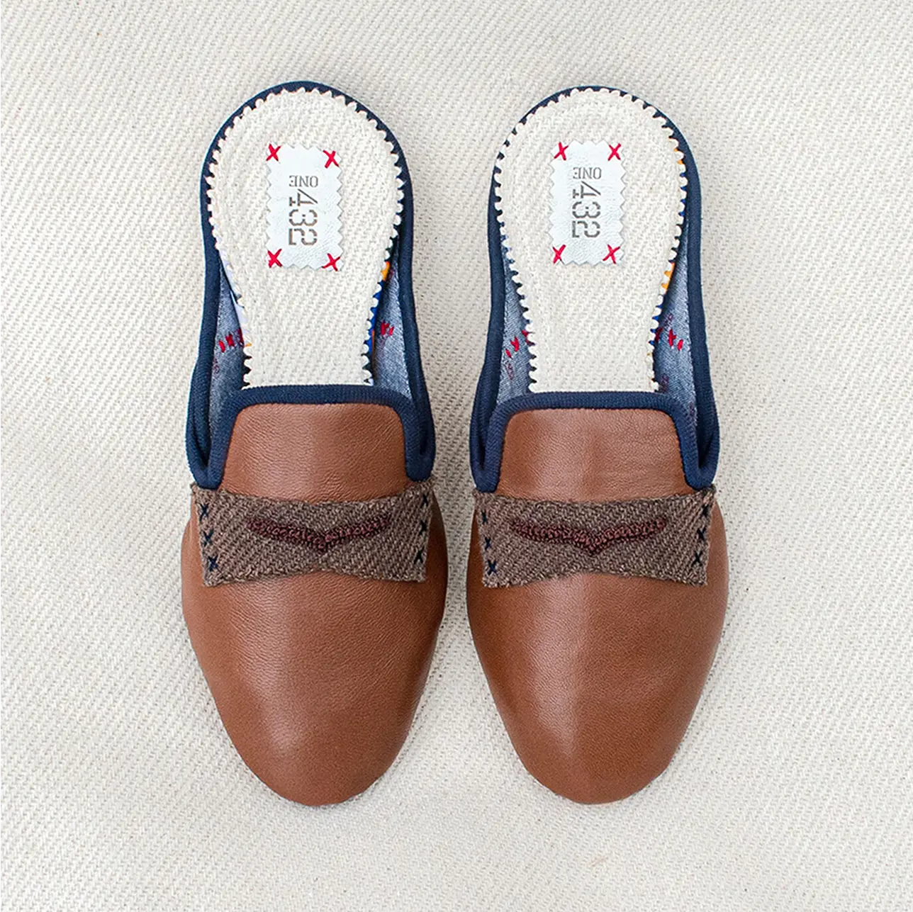 A sleek pair of brown leather slippers with a stylish finish.