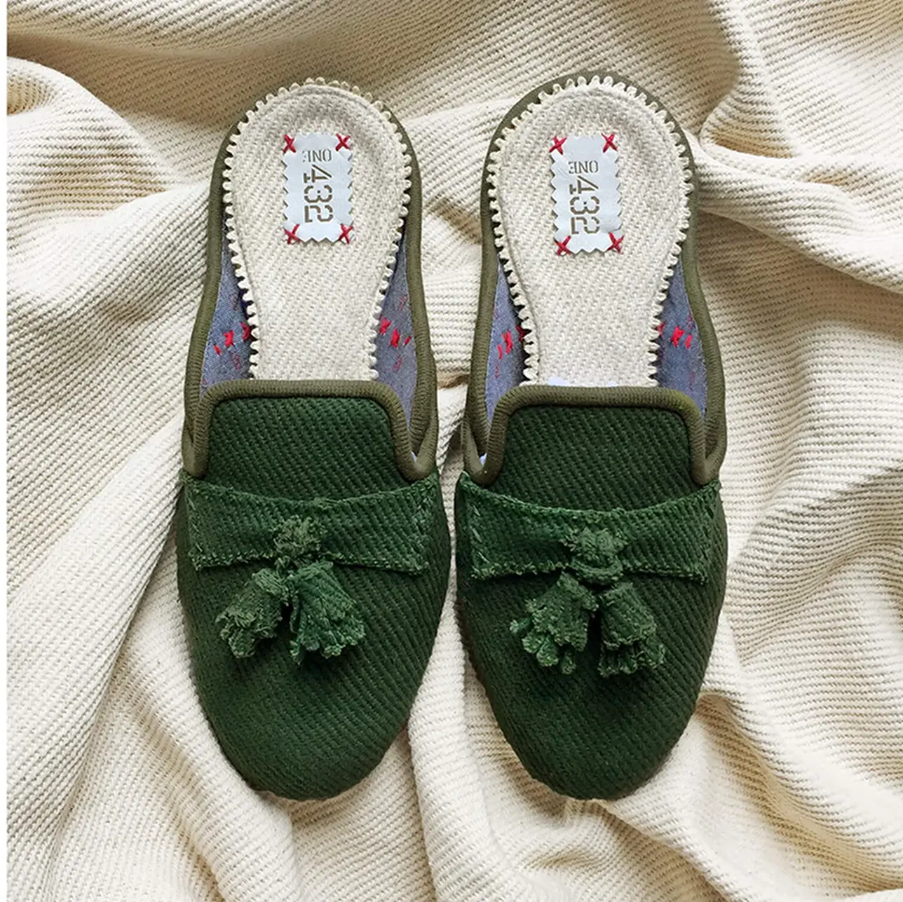 A pair of green cotton slide slippers with a breathable open-toe design.