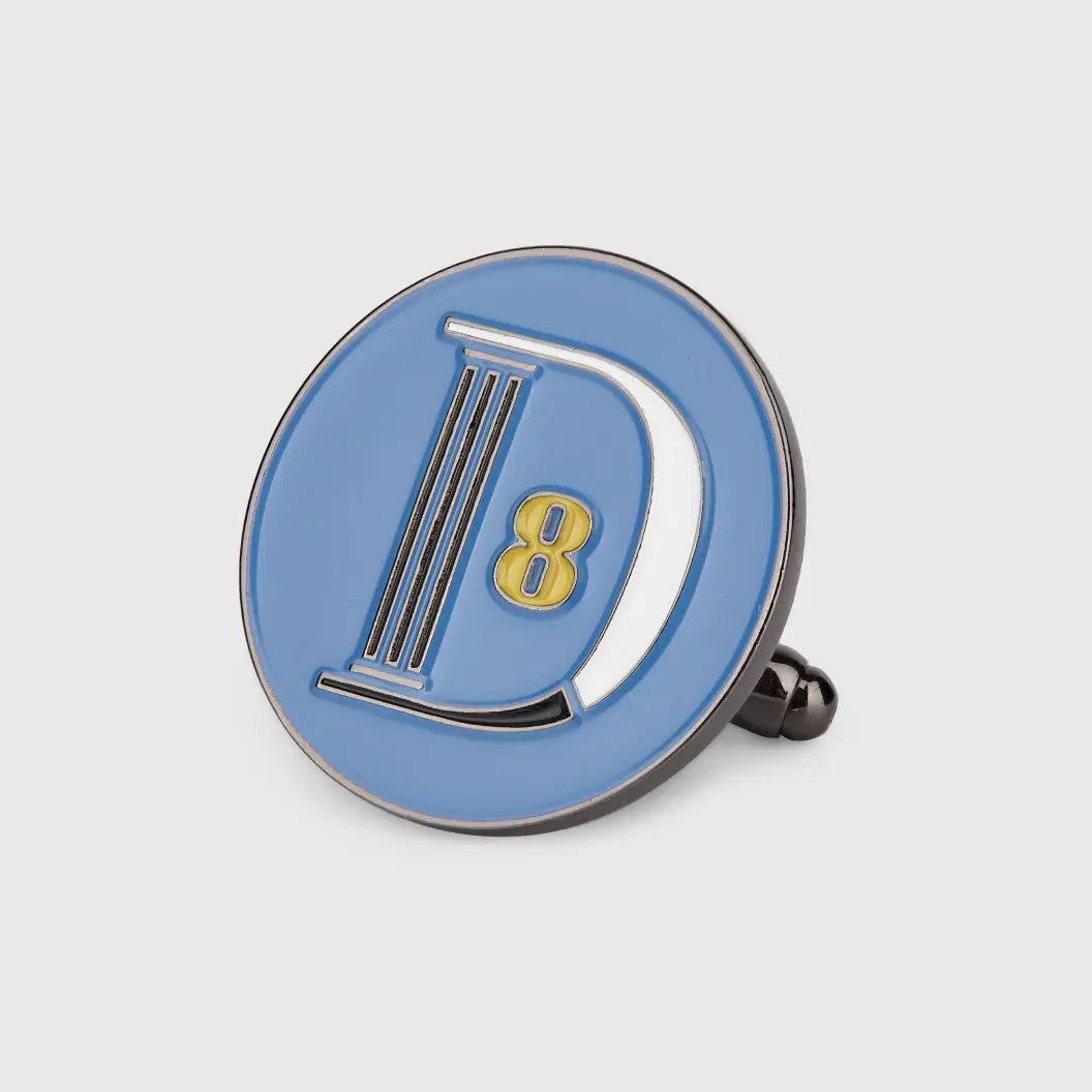 Round enamel pin in blue featuring the letter “D” and the number “8”.