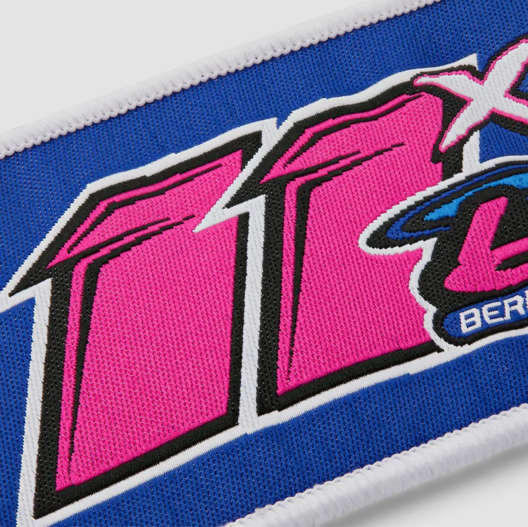 Colorful woven patch with pink, blue, and white text and graphic.