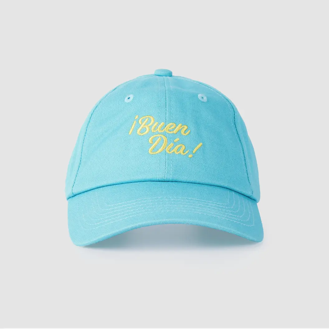 Light blue cap with yellow embroidered text reading ‘¡Buen Día!’ on the front.