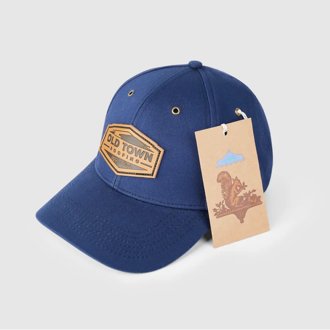 Navy blue cap with brown leather patch reading ‘Old Town Roofing,’ along with a brown hang tag featuring a squirrel.