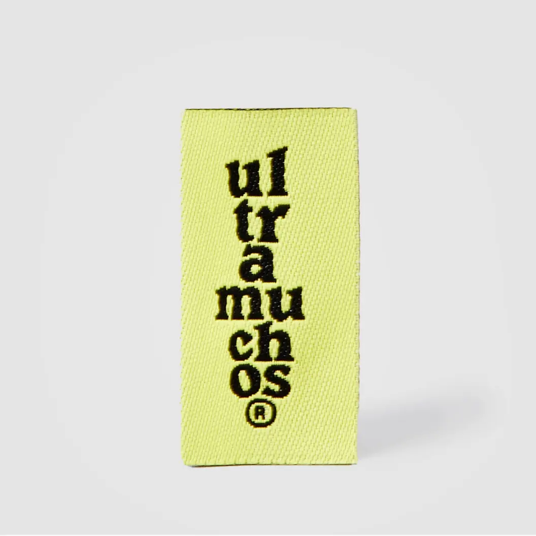 Woven label in vibrant yellow, featuring intricate stitching and clear branding details.