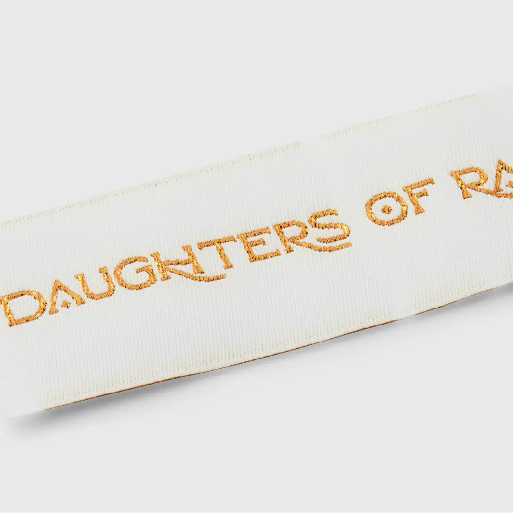 Woven white label with structured design and elegant gold text for a luxurious appearance.