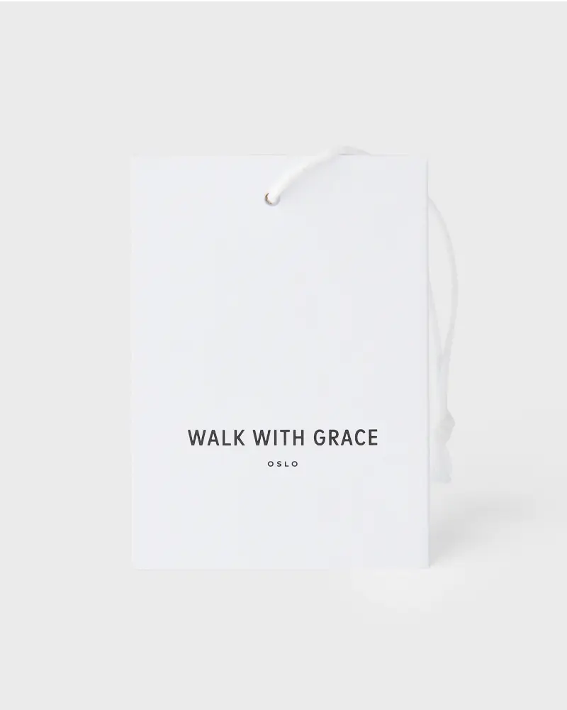 Minimalist white hang tag with black text reading “WALK WITH GRACE” and “OSLO,” attached with a white string