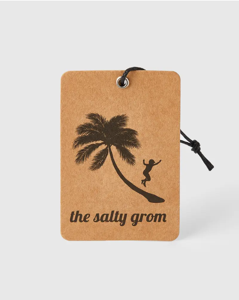 Kraft-colored hang tag featuring a black illustration of a palm tree and a silhouette of a person surfing a wave, with black string attached.