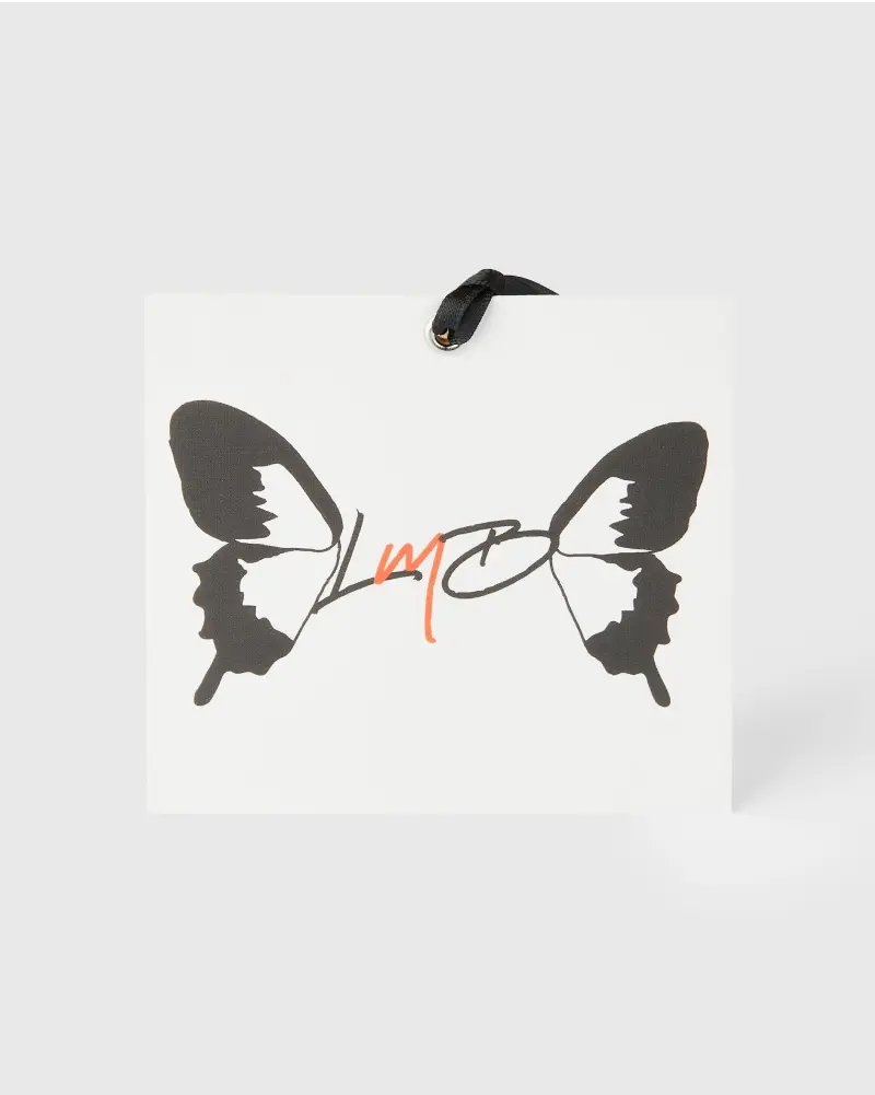 Square white hang tag with a butterfly illustration and the letters “LMP” in an artistic script across the wings, attached with a black ribbon.