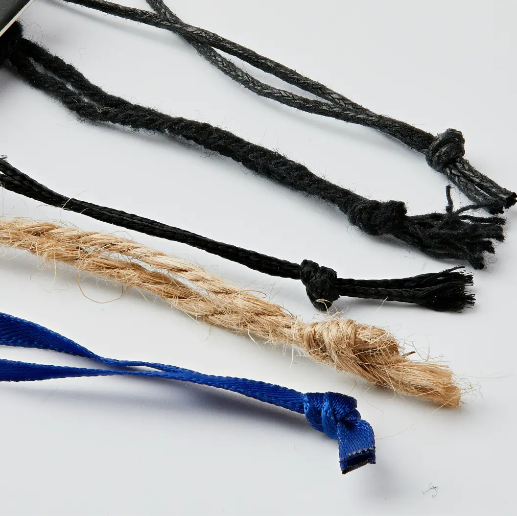 Different types of string materials, including black rope, natural jute, and blue fabric, displayed in a row.