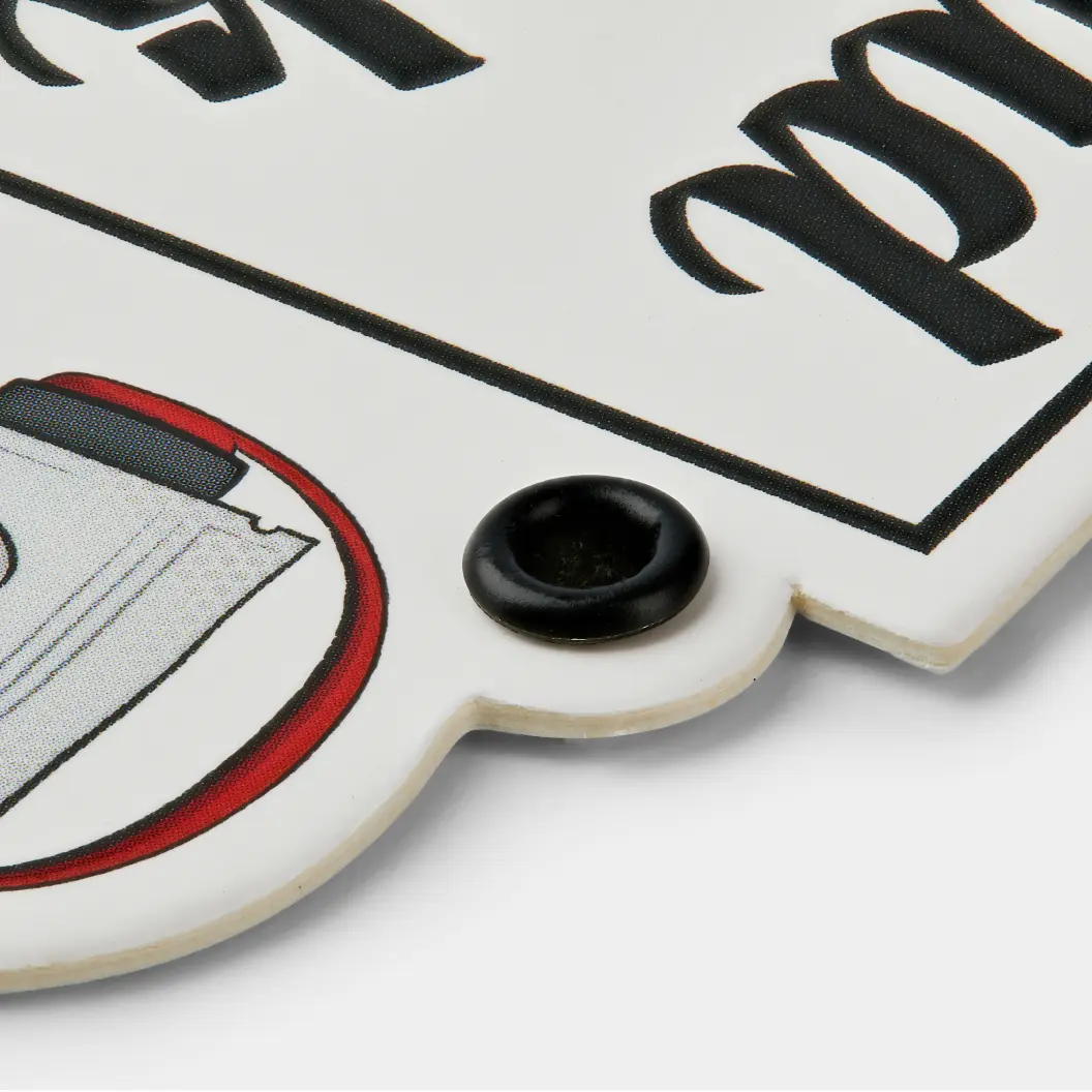 Detailed close-up of a grommet hole on a thick, white, custom-shaped tag with a red and black printed design.