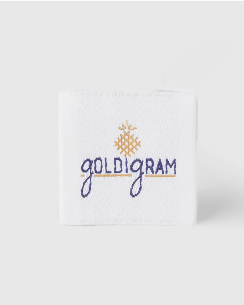 White woven label with violet and gold design featuring the text “Goldigram.”