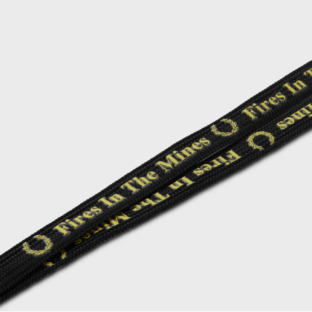 Black lanyard featuring repeating wreath illustrations and yellow “Fires In The Mines” text.