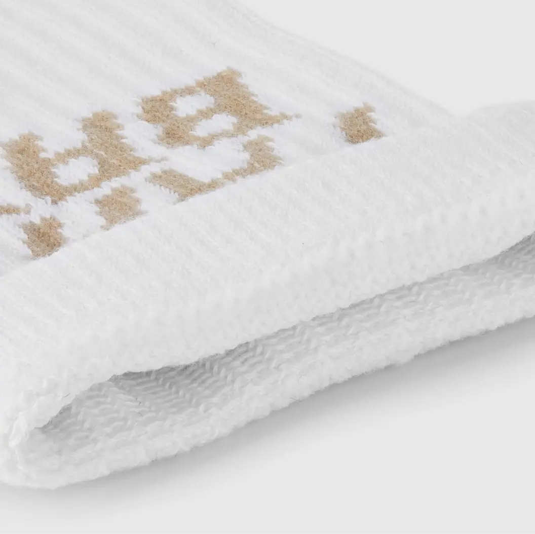 Close-up of white custom socks with gold embroidered text, showcasing fine knit detailing.