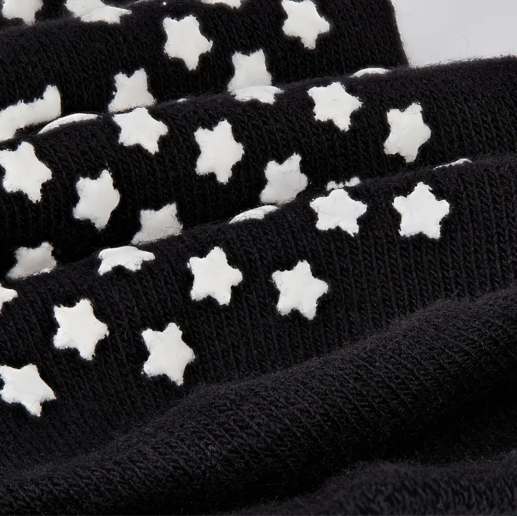 Black custom socks with white star-shaped grips, highlighting the textured, non-slip design.