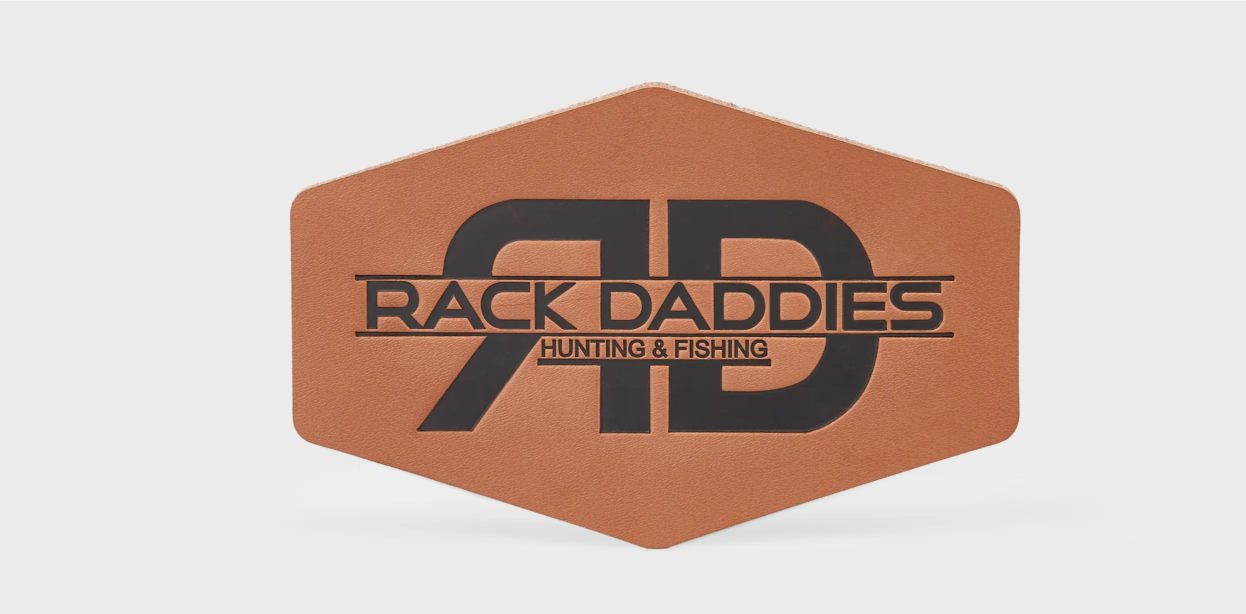 Custom brown leather patch with sleek black design featuring the brand name “Rack Daddies Hunting & Fishing.”