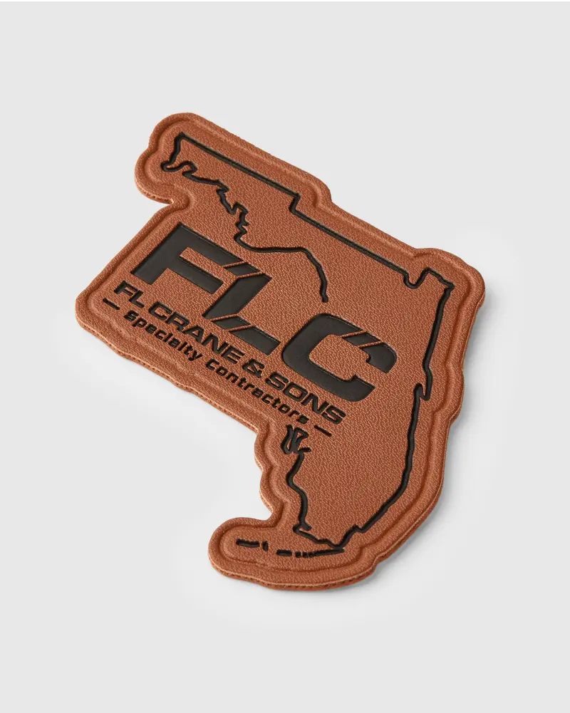 Custom-shaped brown leather patch in the shape of Florida, showcasing bold black logo for FL Crane & Sons Specialty Contractors.