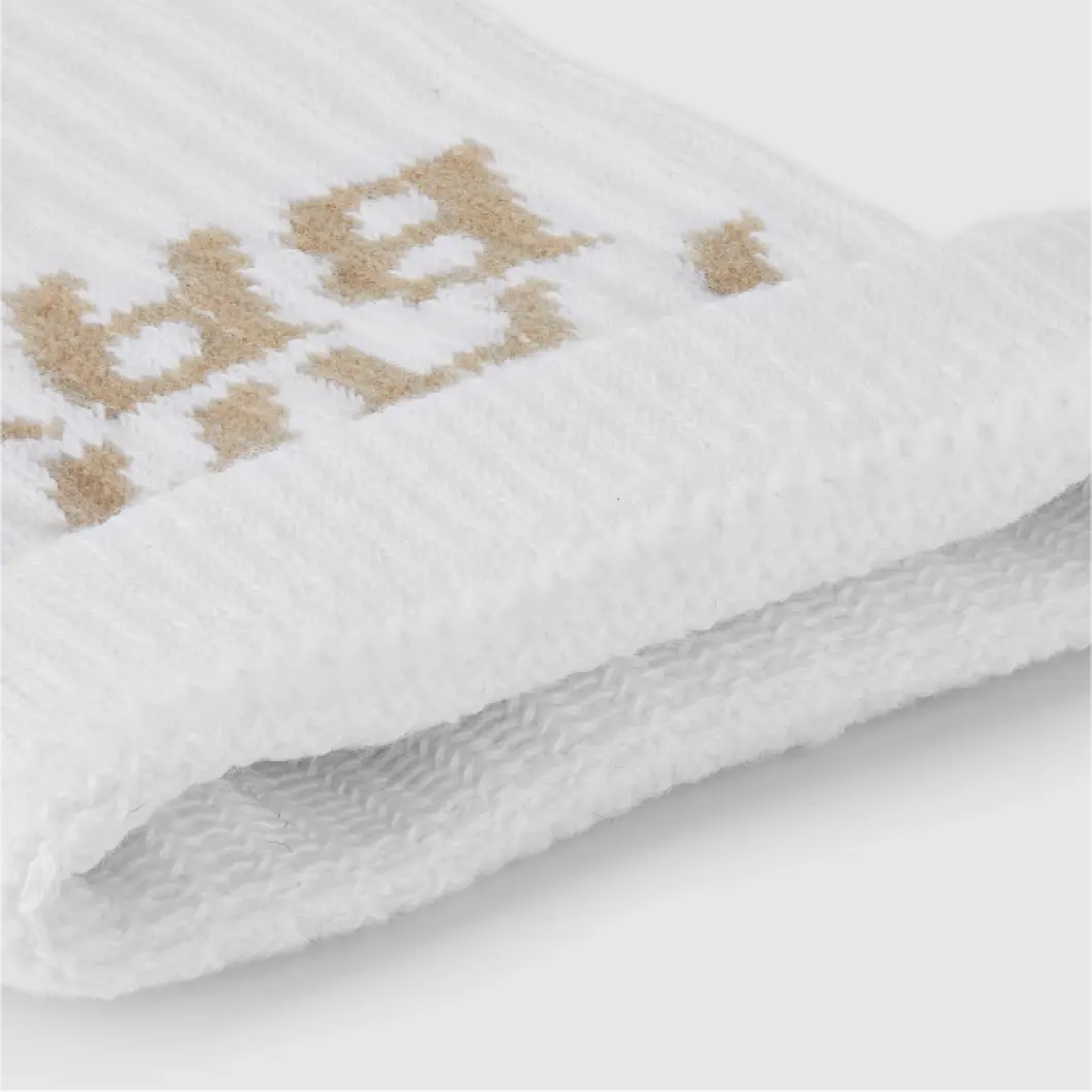 Close-up of a folded white knitted fabric with a gold pattern.