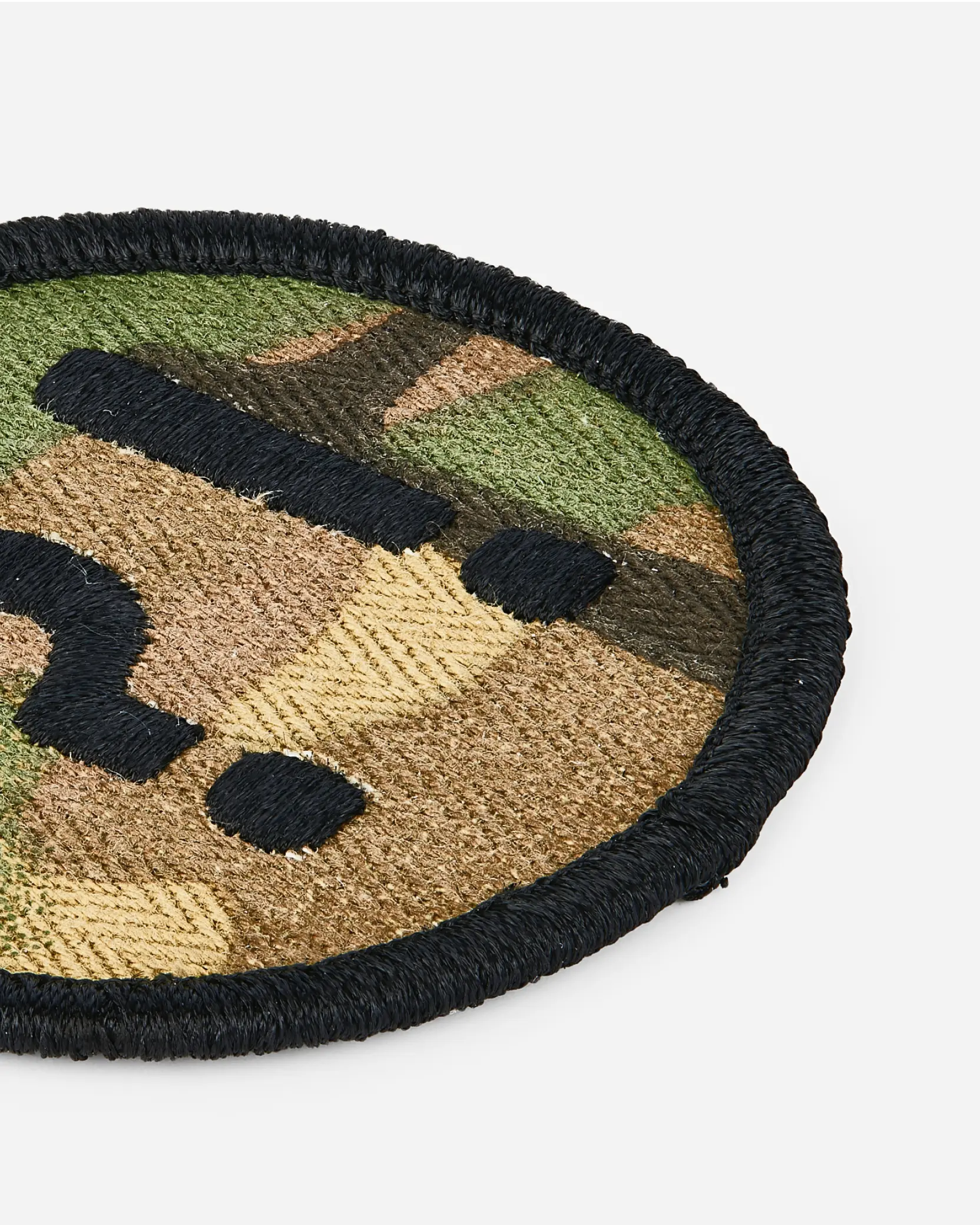 Close-up view of camouflage-patterned round embroidered patch with merrowed border.