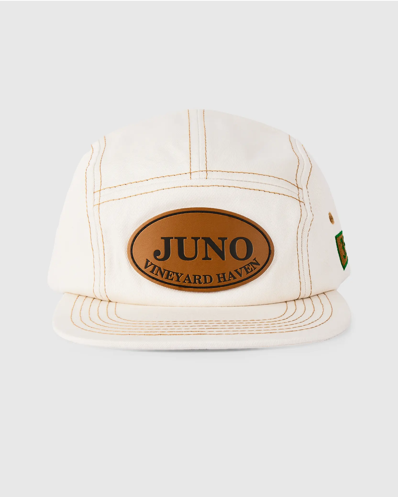 White 6-panel hat with a brown leather patch featuring the word ‘Juno.’