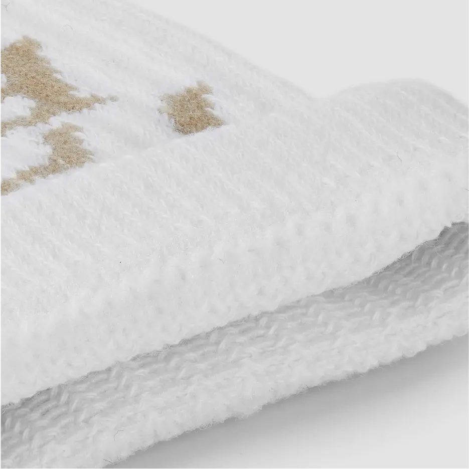 Detailed close-up of white sock knit fabric with beige embroidery