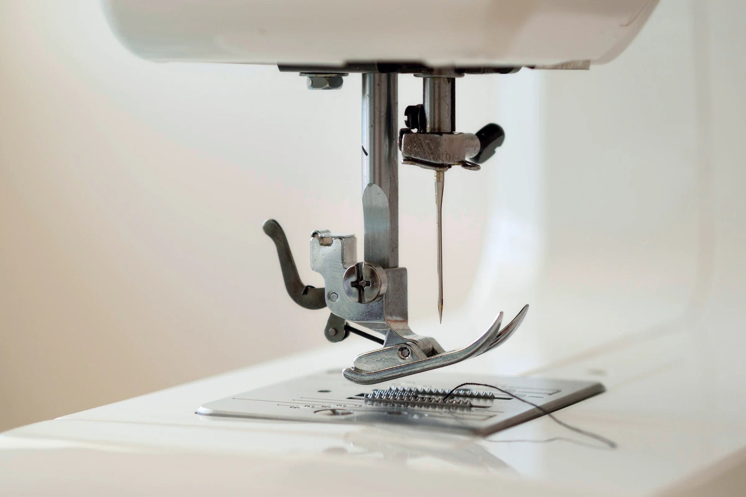 A close-up of a sewing machine needle in a well-lit workspace.