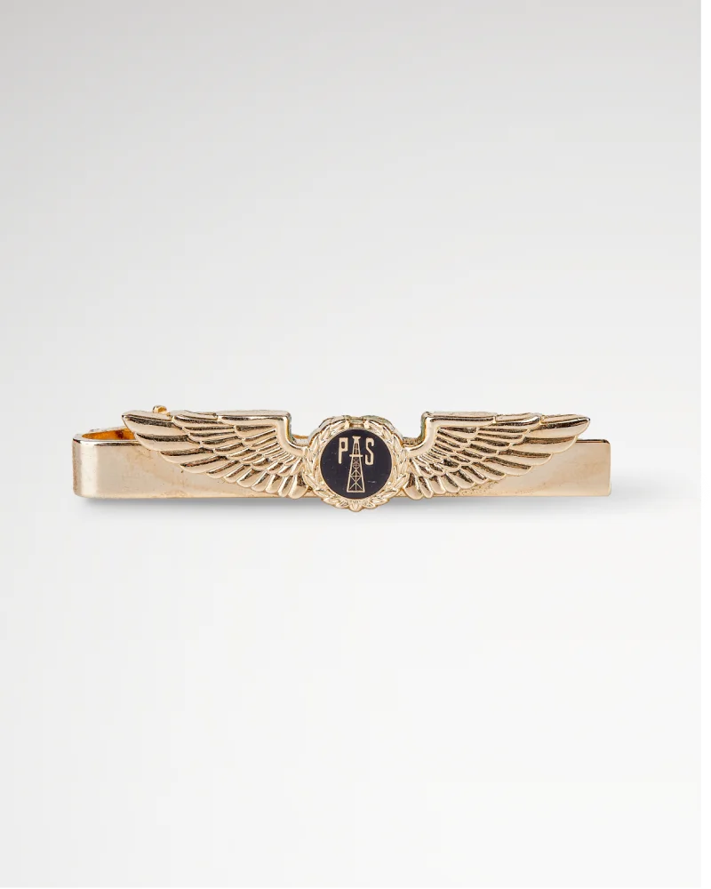 Gold tie bar with winged emblem and “PAS” engraved in the center.