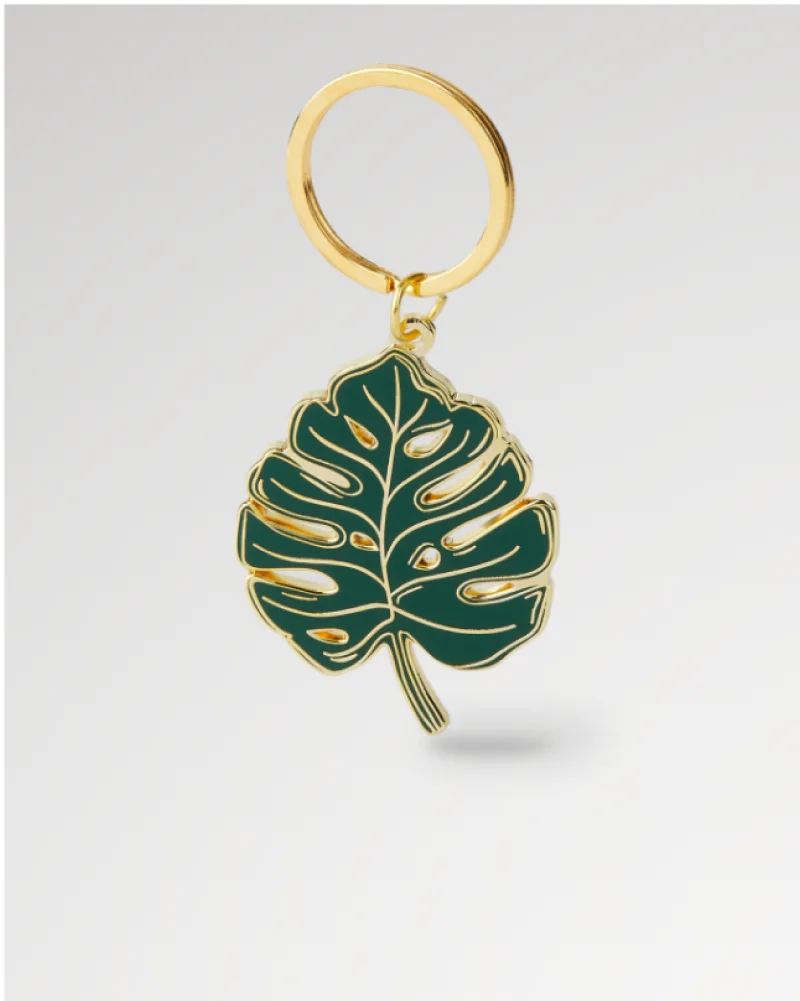 Gold and green enamel keychain shaped like a Monstera leaf